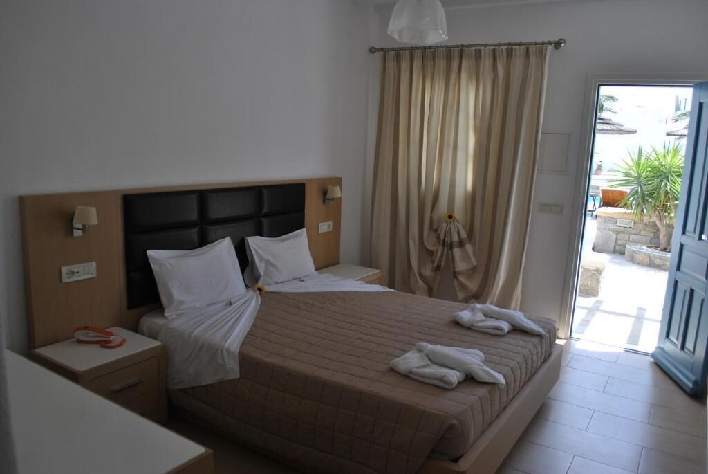 Una habitación de hotel con una cama, una mesita de noche, una lámpara y vistas al exterior.