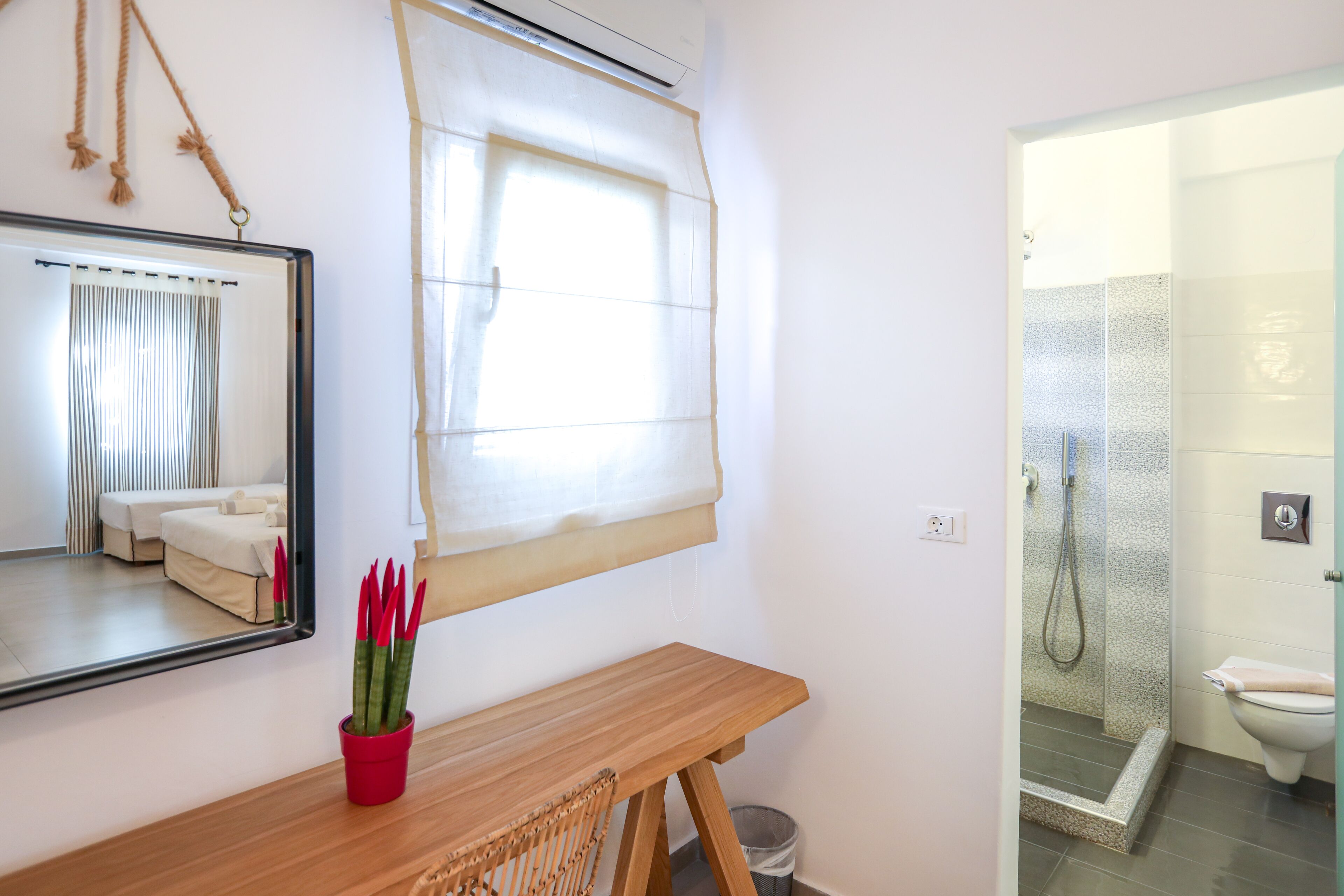 A bathroom with a shower, a toilet, and a mirror.