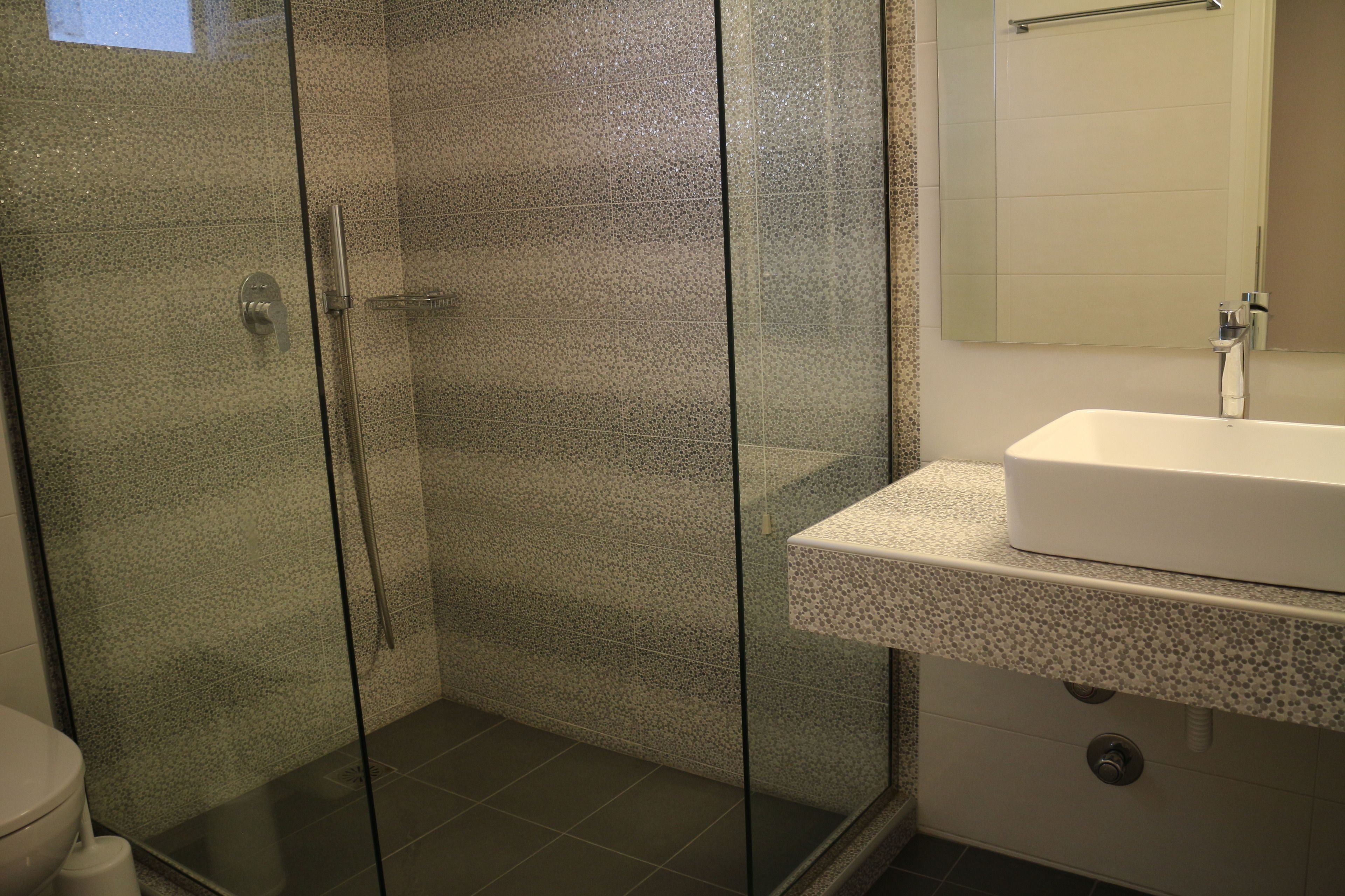 A bathroom with a glass-enclosed shower, a white sink, and a mirror above the sink.