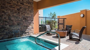 A pool area with a stone wall, outdoor seating, and a clear view of the sky. - Courtyard Columbus (Columbus)