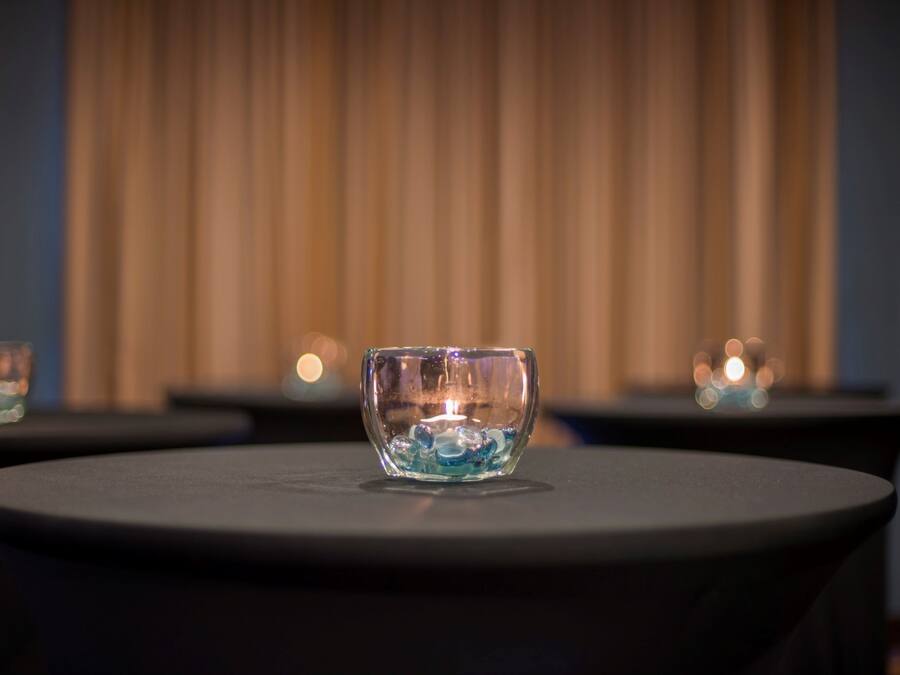 A glass bowl with a candle on a round table.