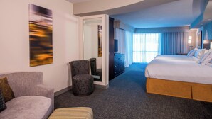 A hotel room with a bed, a sofa, a chair, a small table, and a painting on the wall. - Courtyard Columbus (Columbus)