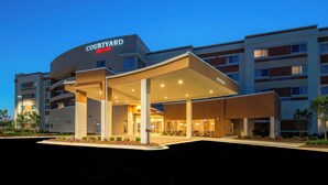 A Courtyard by Marriott hotel with a covered entrance, multiple floors, and a landscaped area in front. - Courtyard Columbus (Columbus)