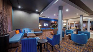 A modern lobby with seating areas, a flat-screen TV, and a reception desk. - Courtyard Columbus (Columbus)
