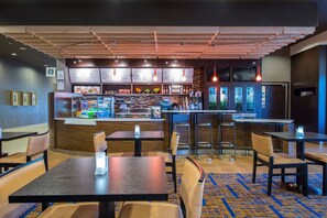A restaurant with wooden ceiling, multiple tables, chairs, a counter with a menu, and a kitchen area. - Courtyard Columbus (Columbus)