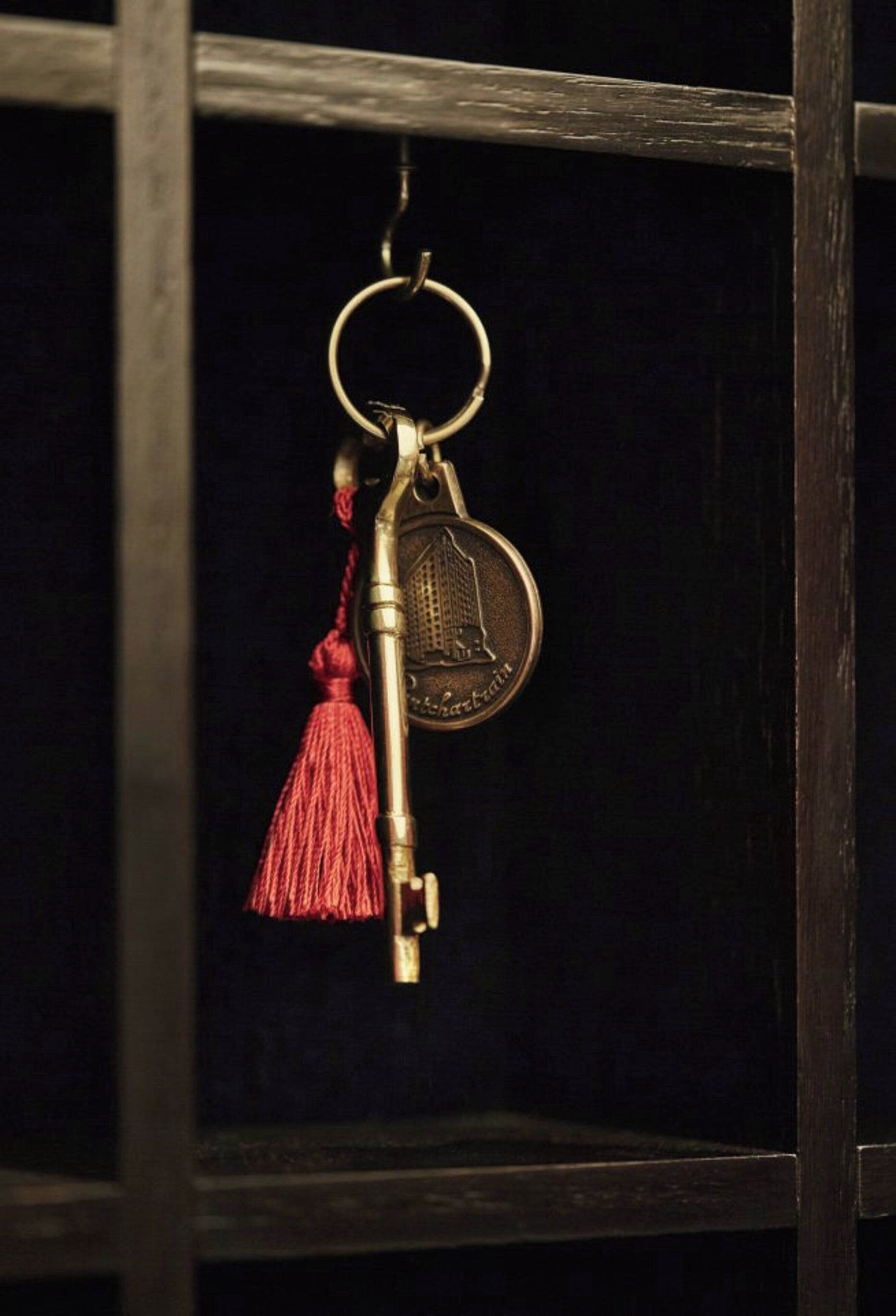 Un llavero con una llave y una moneda, colgado de un aro metálico.