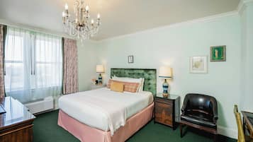 Une chambre d’hôtel avec un lit, une chaise, un bureau, une lampe et un lustre.