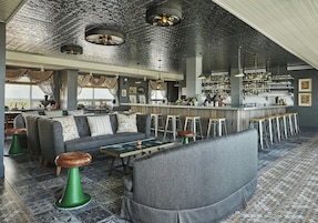 Zona de bar con asientos, una barra y vistas al exterior.