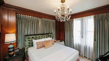 A hotel room with a large bed, a chandelier, and curtains.
