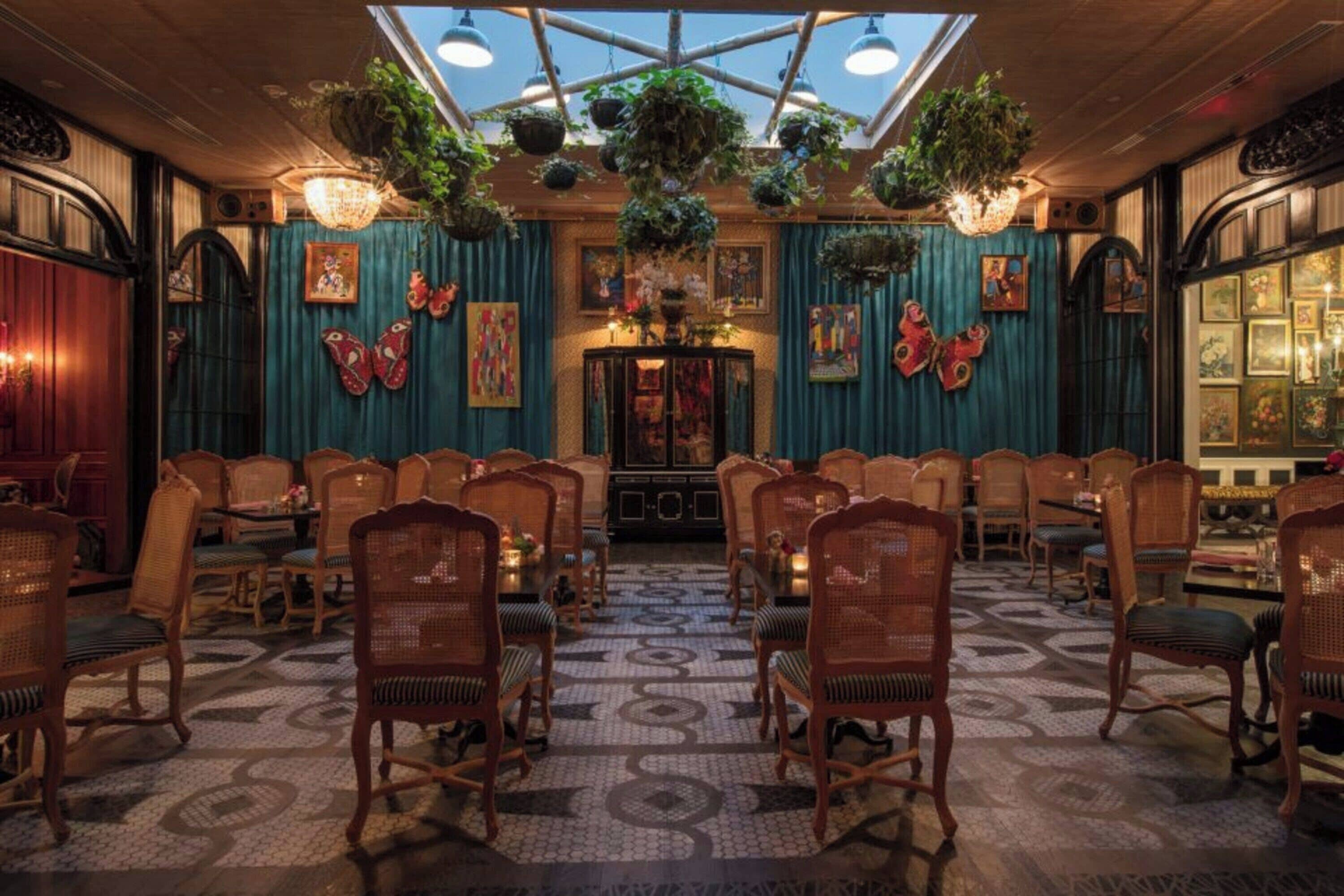 A room with a high ceiling, hanging plants, and a patterned floor.