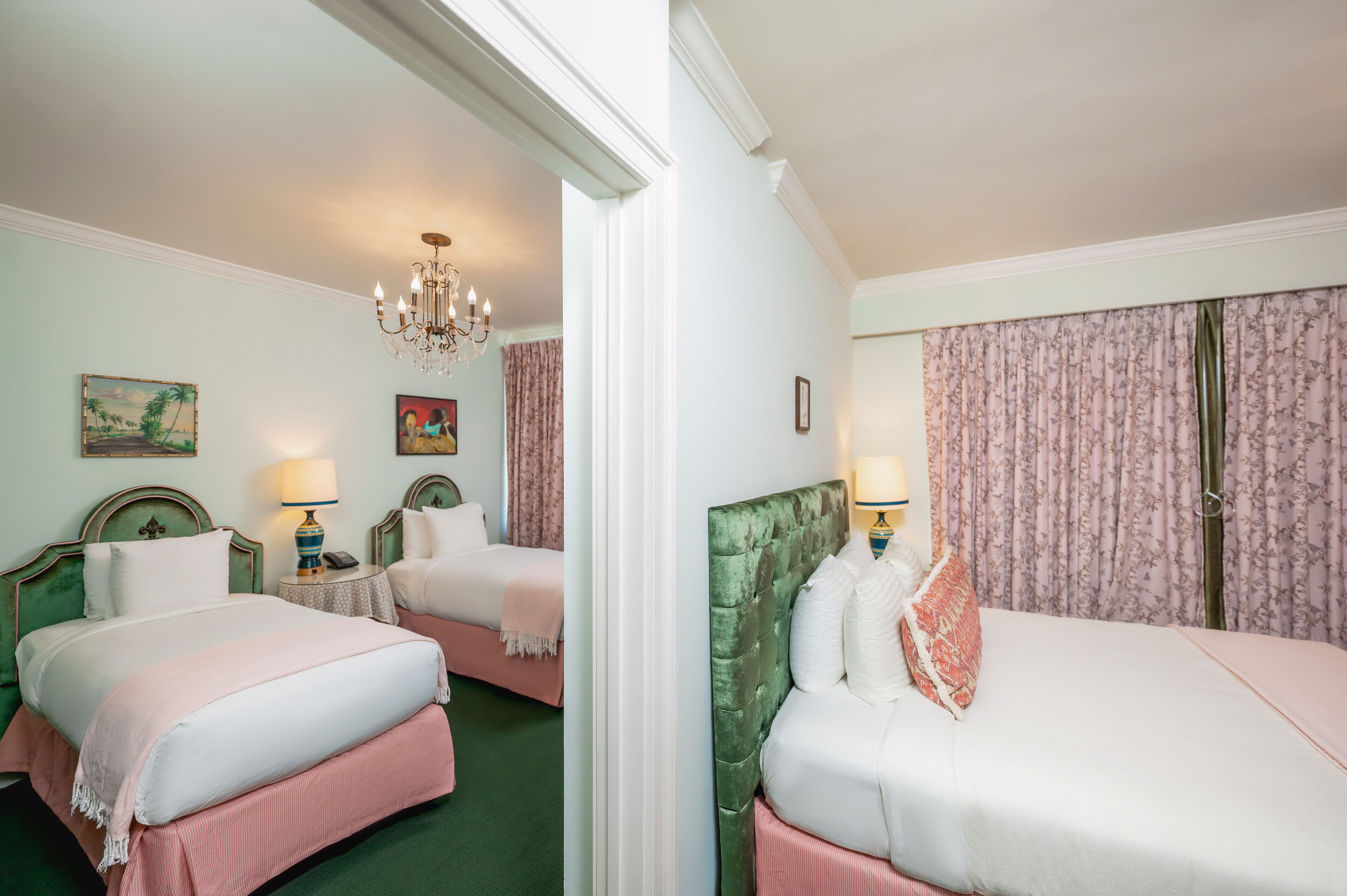 A hotel room with two beds, a chandelier, and floral curtains.
