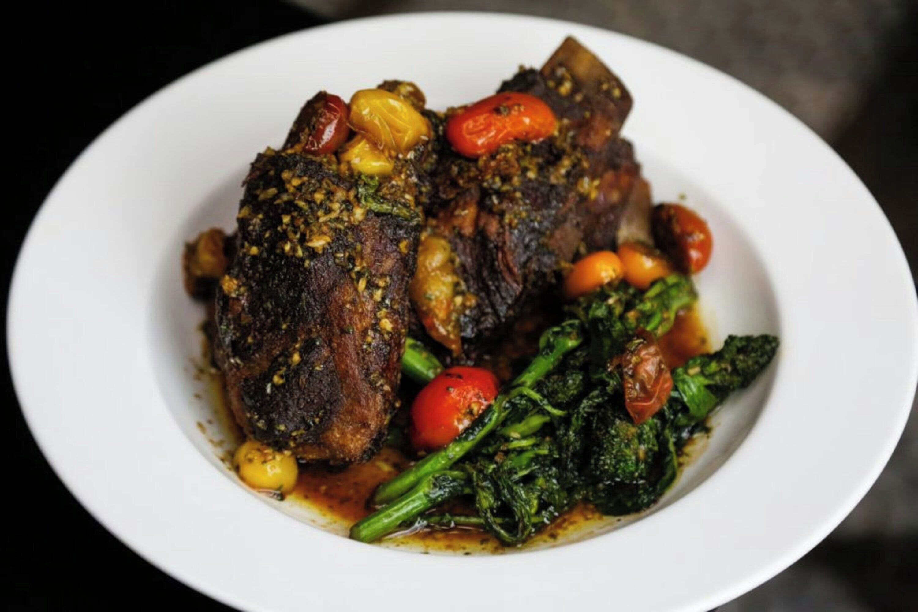 Un plato con dos porciones de carne, verduras y salsa.