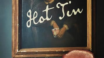 Una obra de arte enmarco con el texto 'Hot Tin' sobre un fondo oscuro.