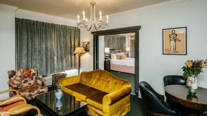 A hotel room with a yellow sofa, a dining table, a mirror, and a chandelier. - The Pontchartrain Hotel (New Orleans)