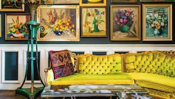 Una habitación con un sofá verde, una mesa de centro de vidrio y una lámpara de pie verde.
