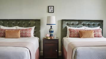 Two twin beds with matching headboards, a bedside table with a lamp, and a framed picture on the wall.