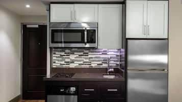 A modern kitchen with stainless steel appliances, dark cabinetry, and a tiled backsplash.