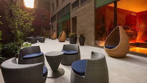 A courtyard with wicker furniture and potted plants.