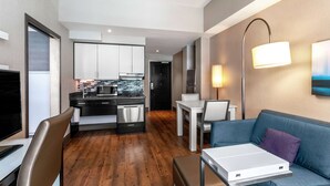 A modern living room with a sofa, a dining table, and a kitchen area in the background.