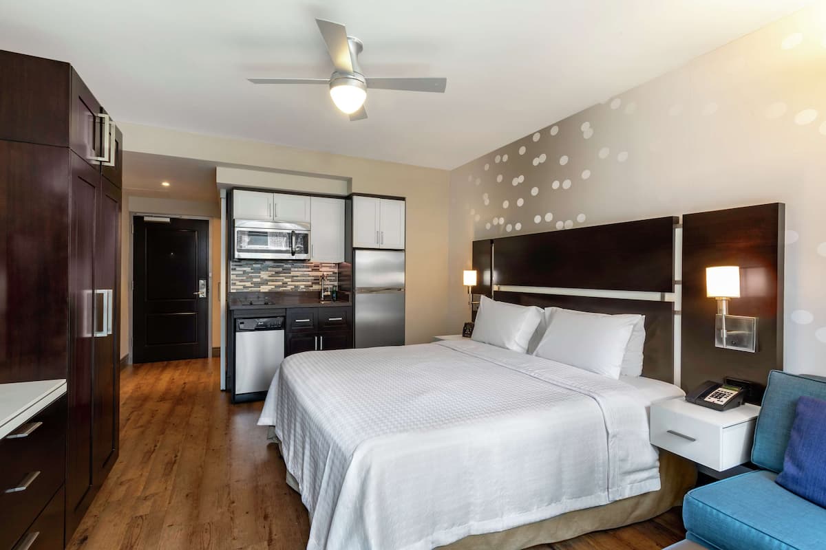 Ein Hotelzimmer mit Bett, Schreibtisch, Stuhl, Mikrowelle und Kühlschrank.