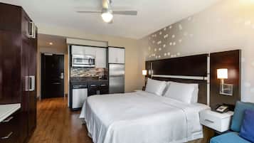 A hotel room with a bed, a desk, a chair, a microwave, and a refrigerator.