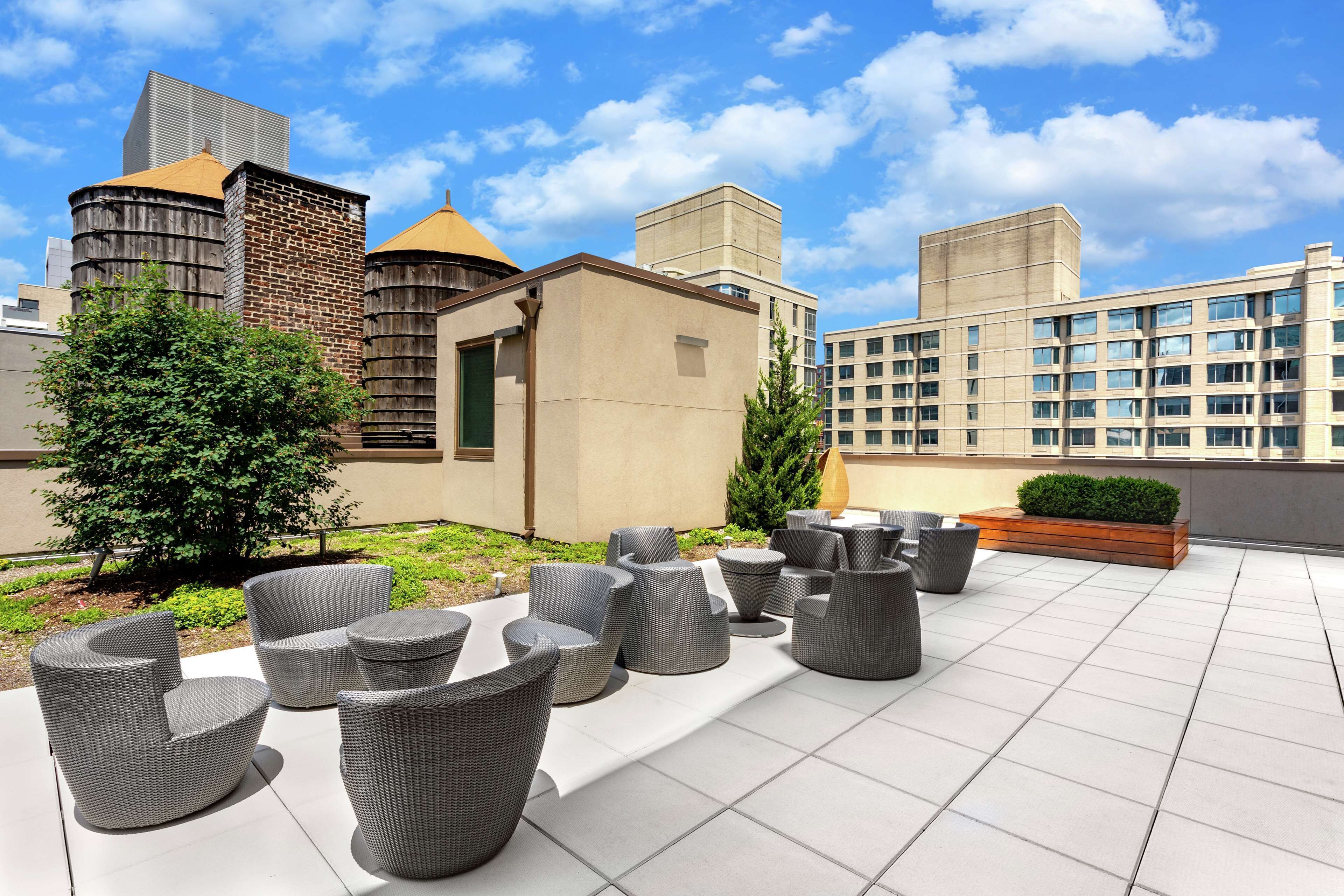 A rooftop patio with outdoor seating and a view of surrounding buildings.