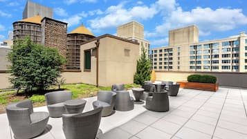 A rooftop patio with outdoor seating and a view of surrounding buildings.