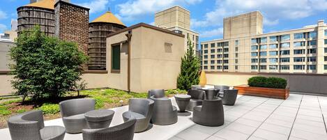 Terraza en la azotea con mobiliario exterior y vistas de edificios circundantes.