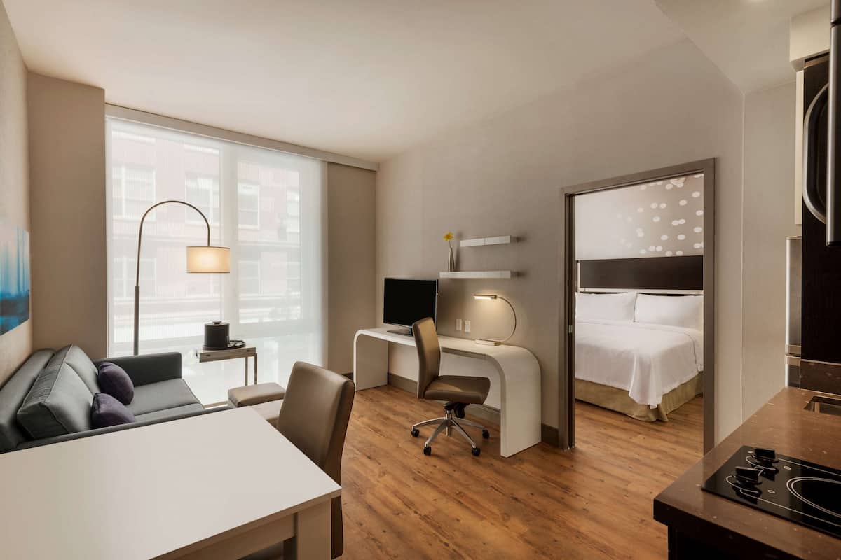 Ein Hotelzimmer mit Bett, Schreibtisch, Stuhl und Essecke.