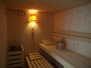 A wooden sauna with benches, a wall-mounted heater, and a clock. - Albergo Ristorante La Baita (Livinallongo del Col di Lana)