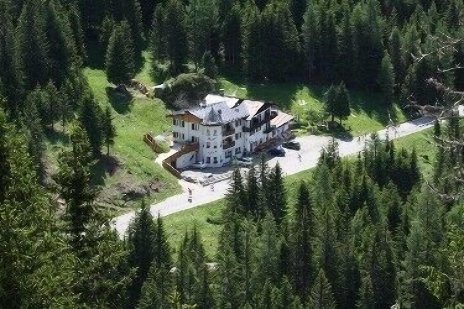 Eine Luftaufnahme eines großen, mehrstöckigen Hauses, umgeben von dichtem Wald.