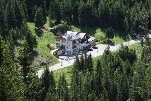 An aerial view of a large, multi-story house surrounded by dense forest.