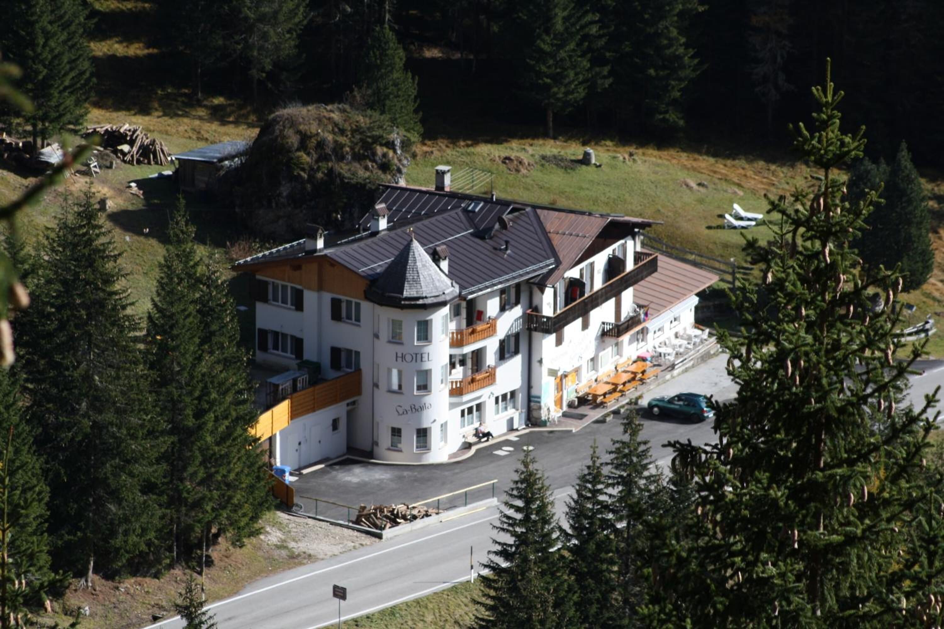 Ein mehrstöckiges Hotel mit einem markanten Ecktürmchen, umgeben von dichtem Wald.