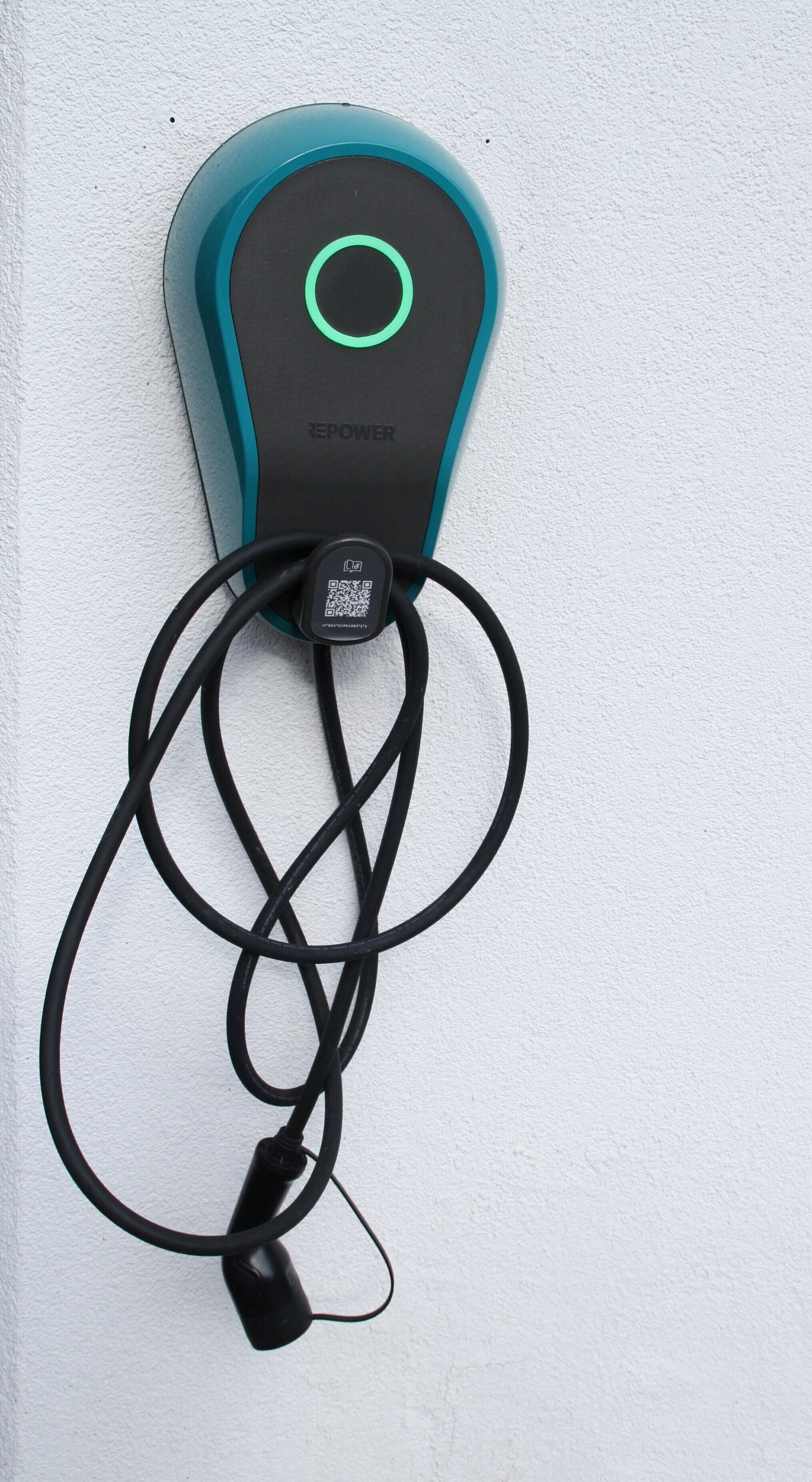 A teal and black electric vehicle charging station with a QR code and a cable connected to it.