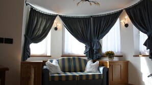 Una stanza accogliente con un divano a righe, un armadietto in legno e una ventola a soffitto.