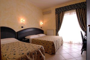 A hotel room with two beds, a radiator, a window with curtains, and a chair. - L'Approdo (Anzio)