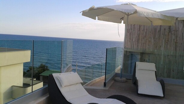 A balcony with two lounge chairs and a large umbrella, overlooking the sea. - L'Approdo (Anzio)