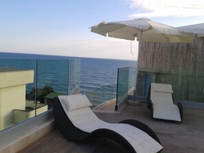 A balcony with two lounge chairs and a large umbrella, overlooking the sea. - L'Approdo (Anzio)