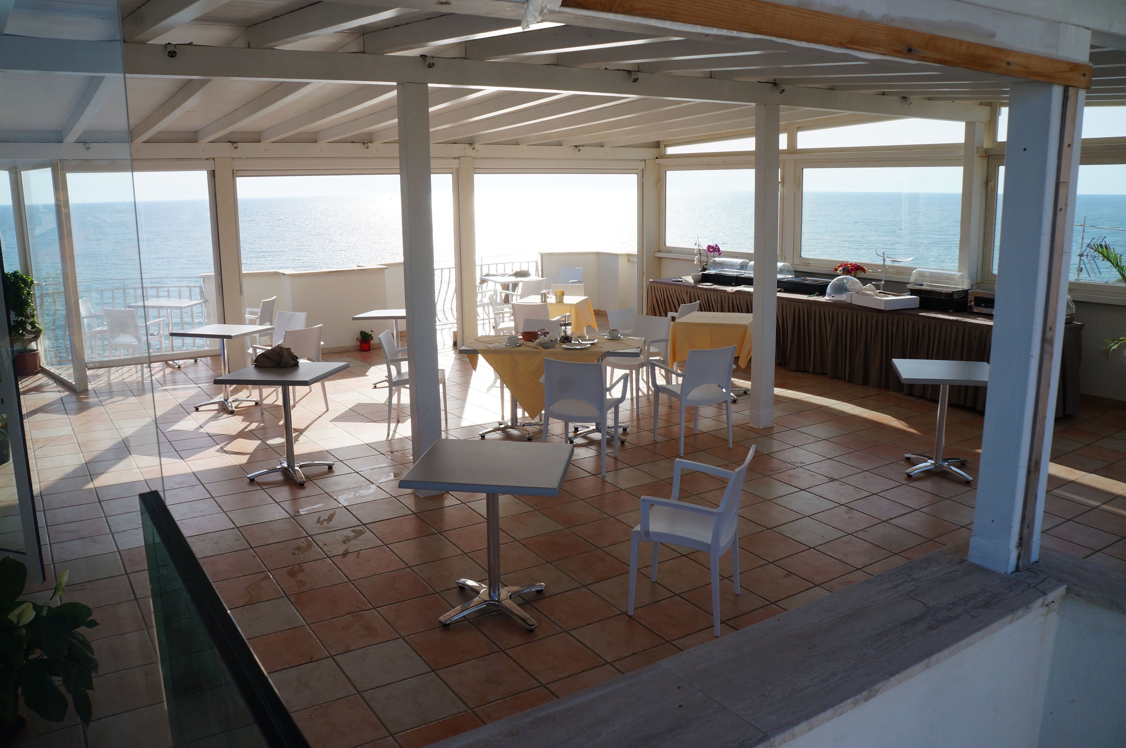 Una terraza cubierta con mesas y sillas, con vistas al mar.