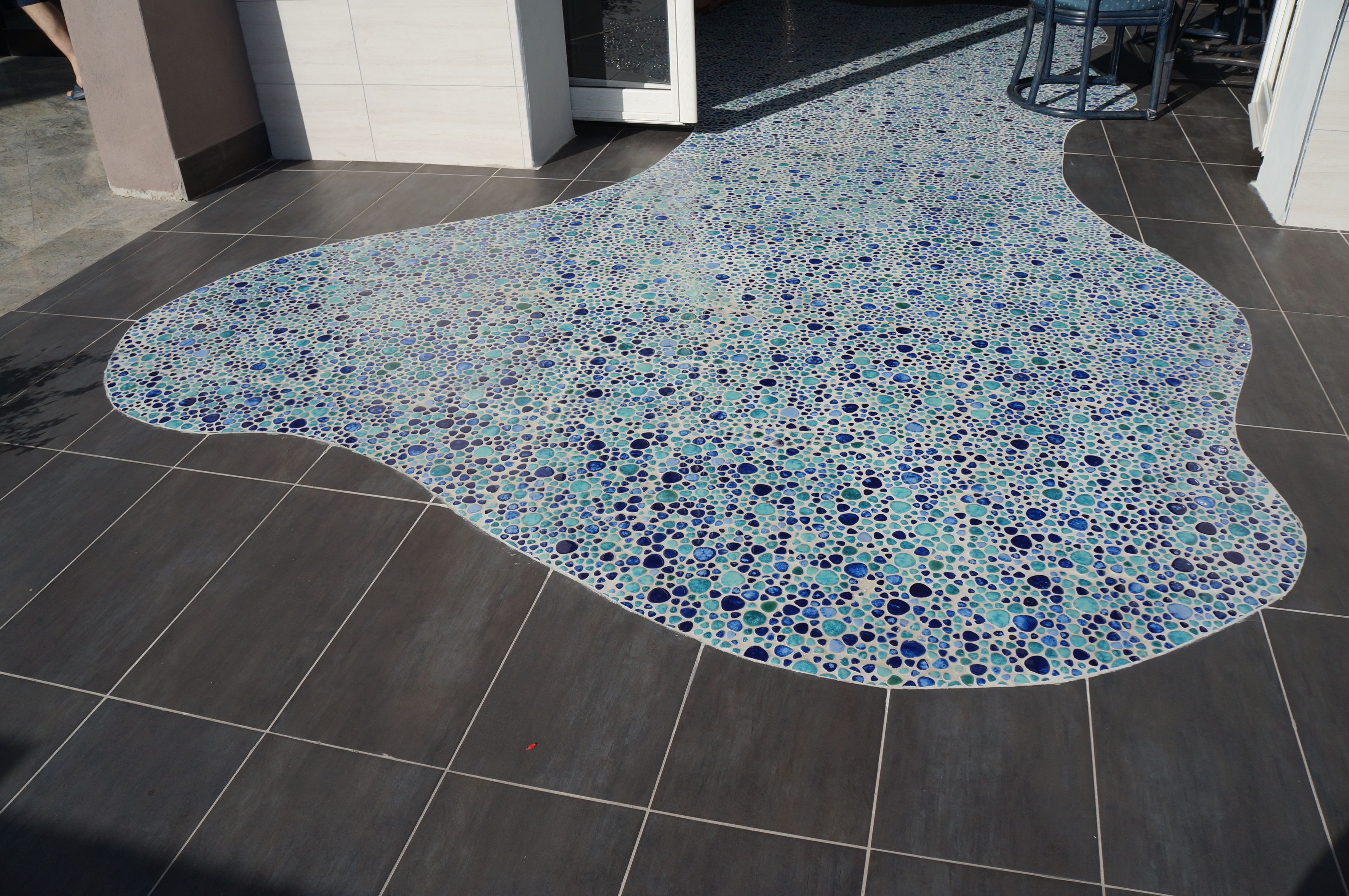 Un sol orné d’une mosaïque aux motifs originaux et recouvert de carreaux foncés.