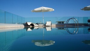 A modern infinity pool with clear blue water, a white umbrella, and lounge chairs. - L'Approdo (Anzio)