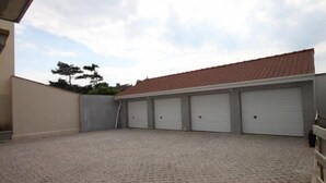 Un edifici amb teulada enrajolada i quatre portes de garatge blanques.