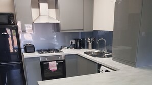 A modern kitchen with grey cabinets, a built-in oven, a sink, and a stainless steel refrigerator. - May's House (Liverpool)