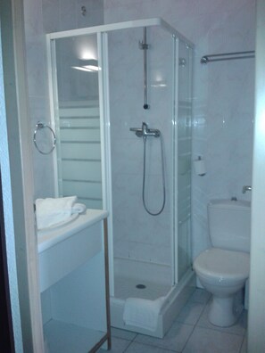 Une salle de bain moderne dotée d’une douche à parois de verre, de toilettes et d’un lavabo.