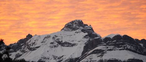A snow-covered mountain peak with a sunset sky.