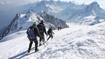 Un grupo de excursionistas en un sendero nevado de montaña con vistas a picos distantes.