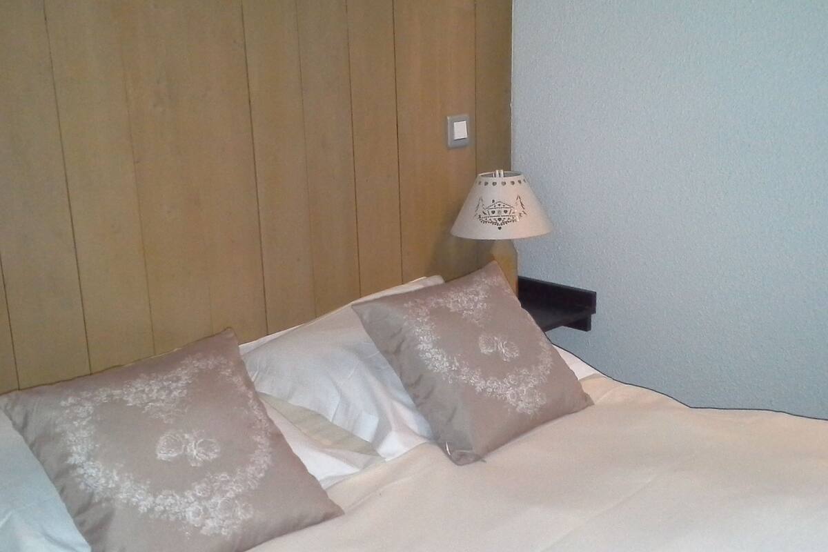 Un lit avec deux oreillers, une table de chevet avec une lampe et une tête de lit en bois.