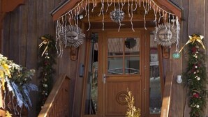 Een houten gebouw met een sneeuwbedekte dak, een houten trap en een voordeur met een krans.