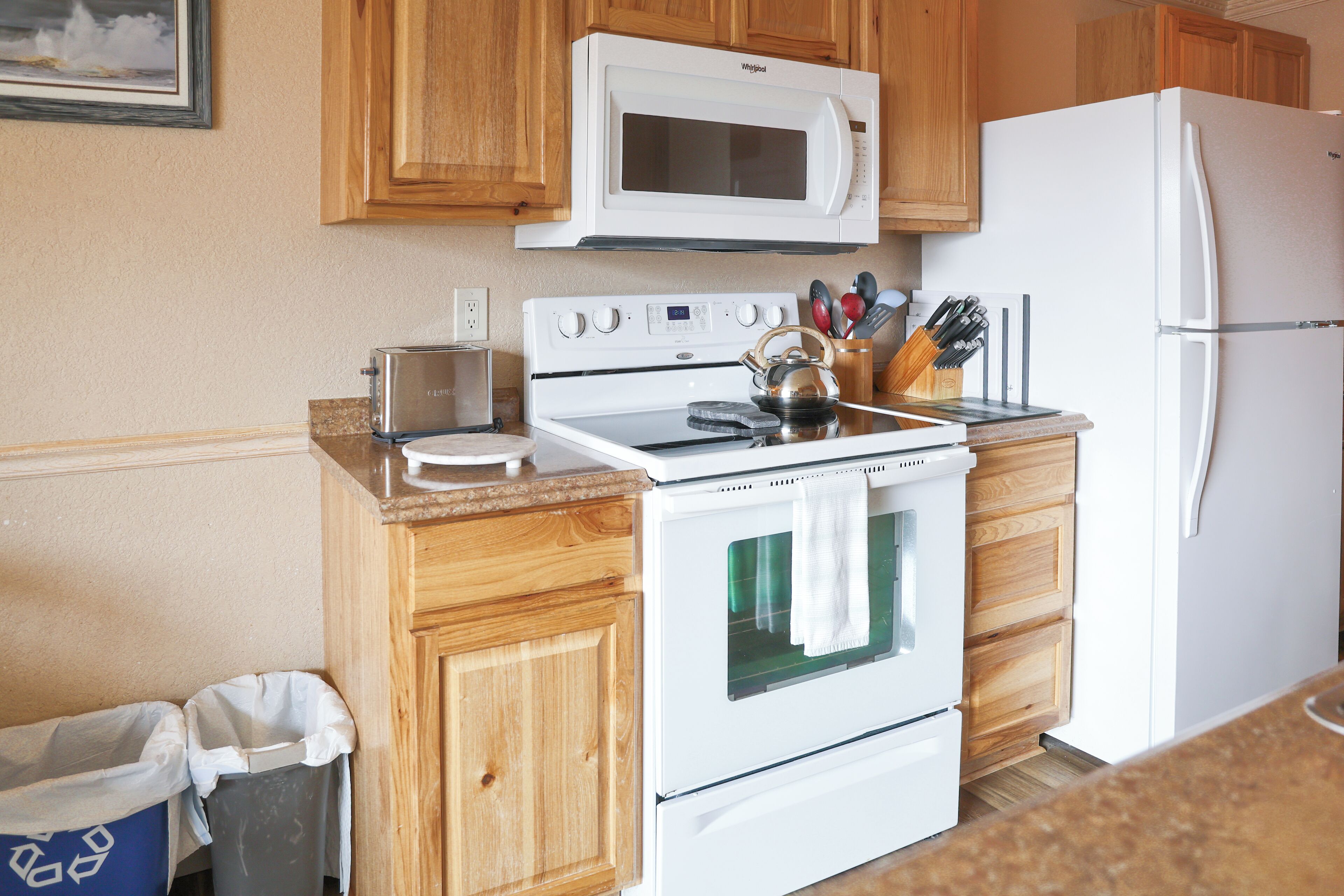 Una cucina compatta con mobili in legno, un piano cottura bianco, un forno a microonde e un frigorifero.
