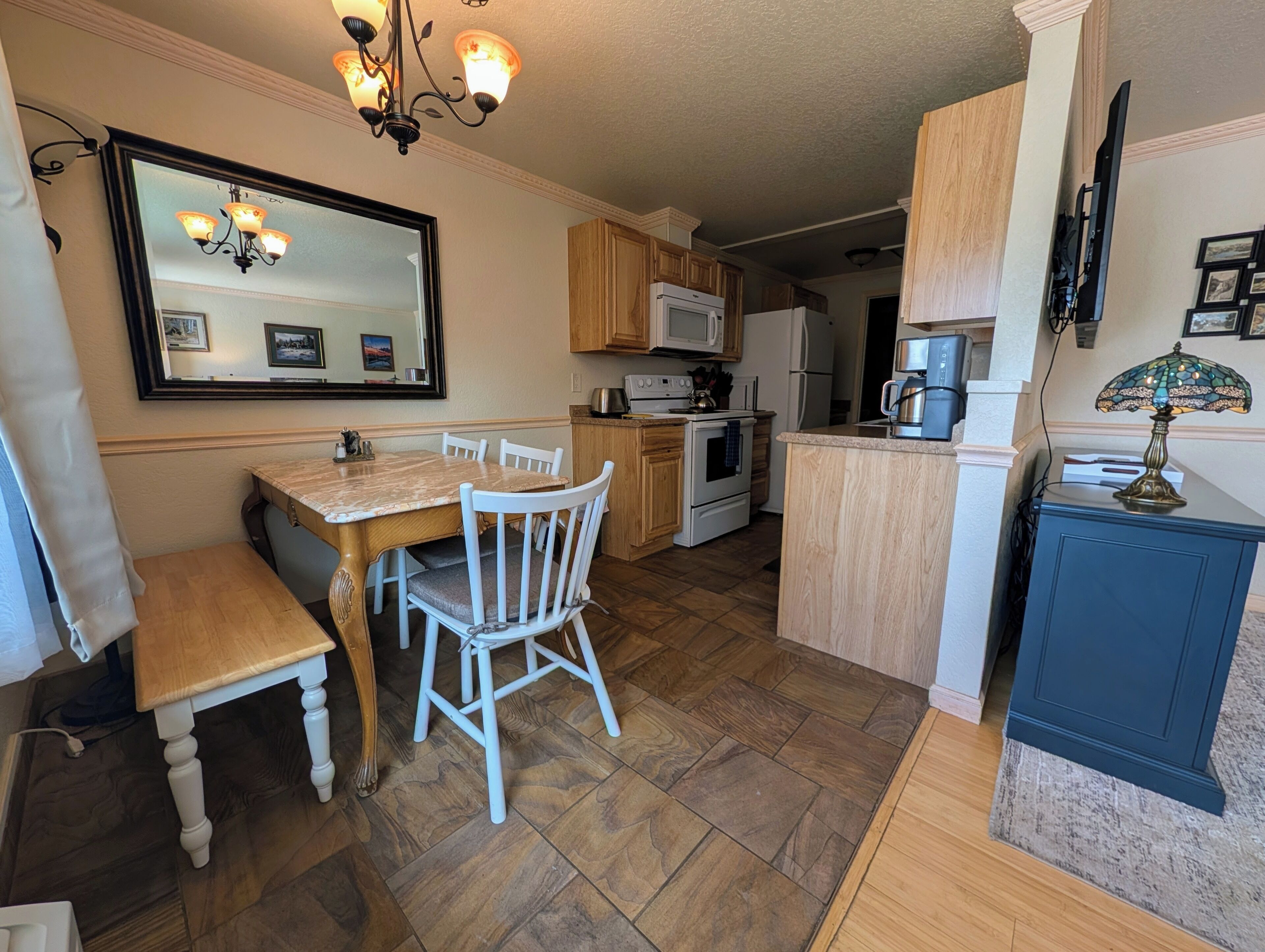 A kitchen with wooden cabinets, a dining table with chairs, a chandelier, and a microwave.
